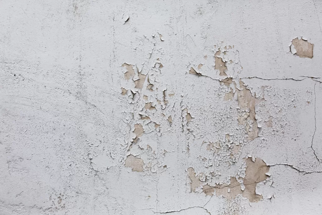 Närbild av en fasad som visar tydliga skador såsom sprickor och avflagningar.
